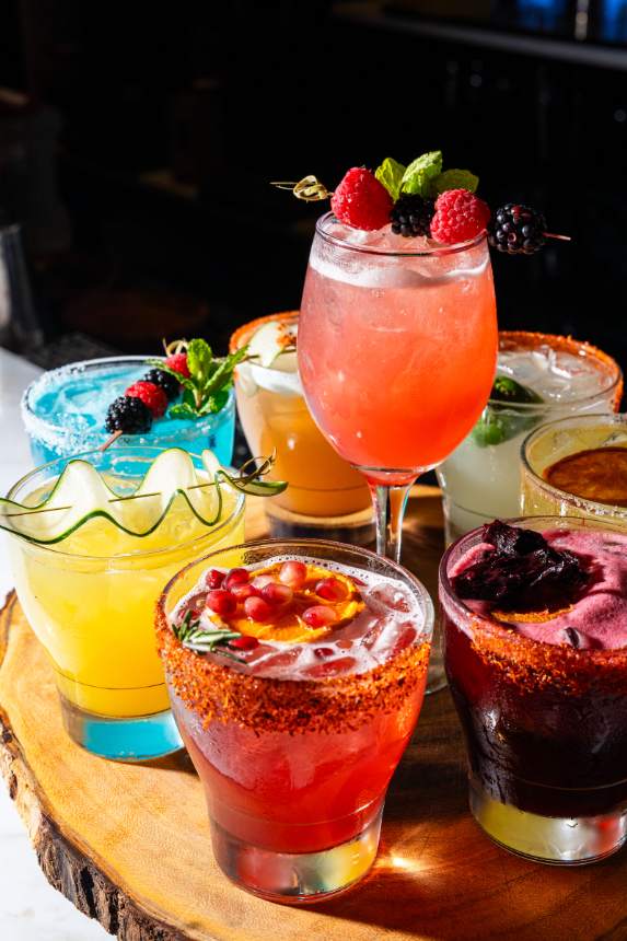 A board of margaritas and cocktails with chile-salt rims and fruit garnish